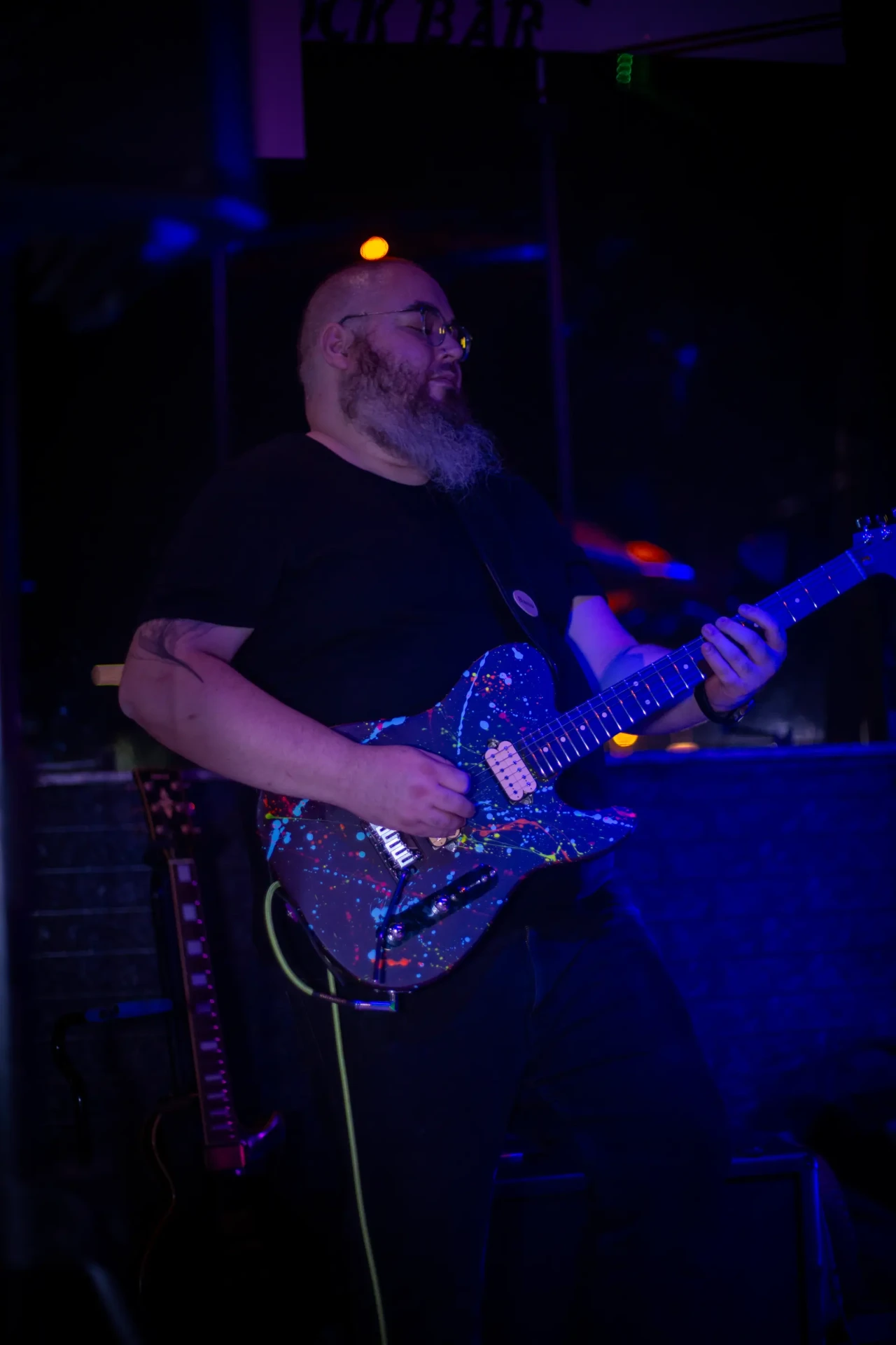 Hugo Rosso solando na guitarra sob luz azul